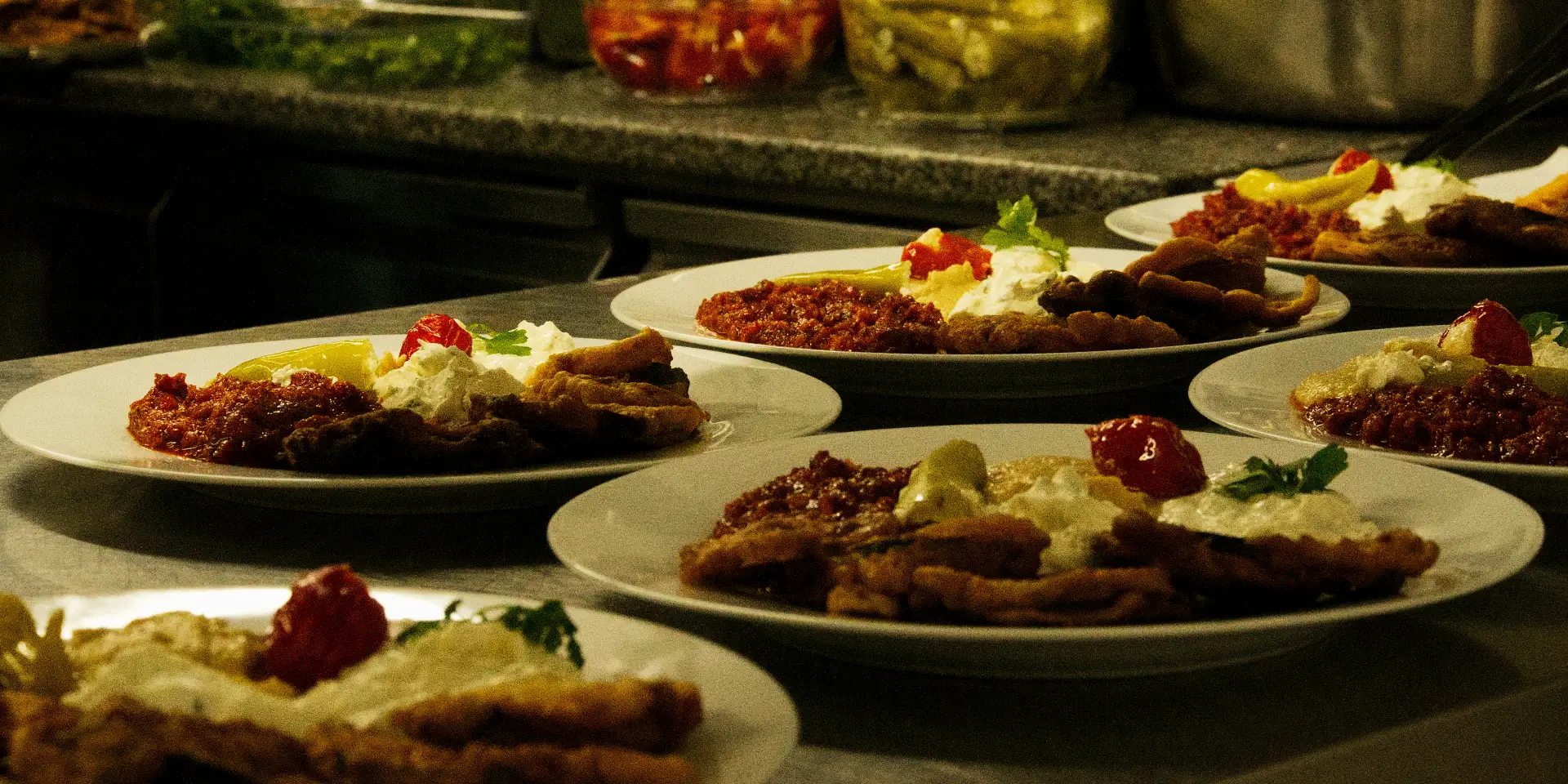 Mehrere Teller mit identisch angerichtetem türkischem Gericht in der Küche für Catering in Nürnberg vorbereitet
